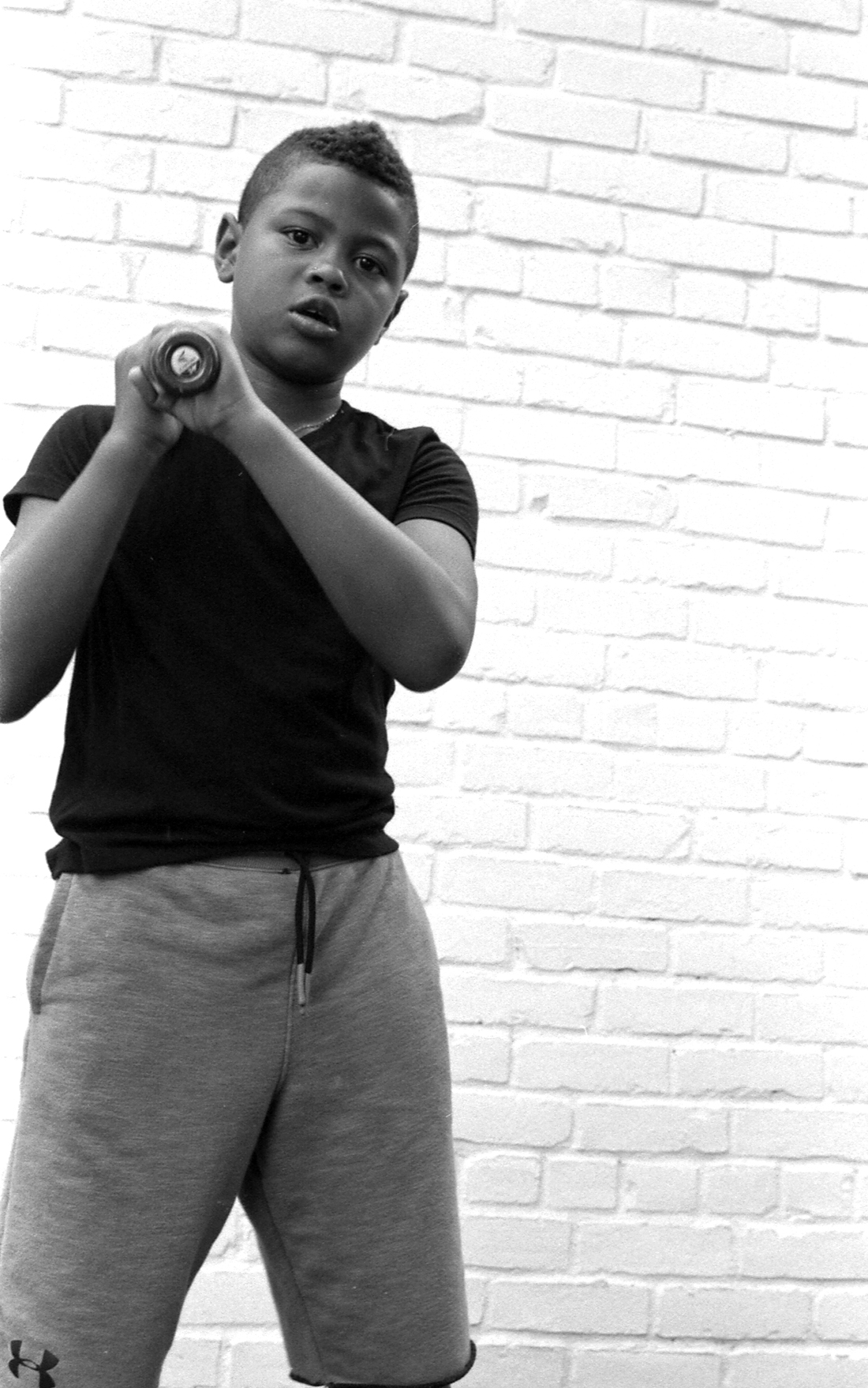 Young Boy with a black t-shirt swinging a baseball bat